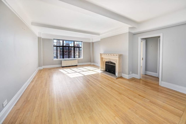 unfurnished living room featuring beam ceiling and light hardwood / wood-style flooring