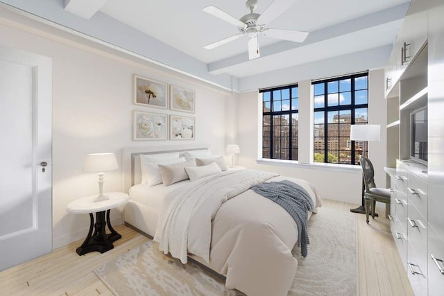 bedroom with beamed ceiling, ceiling fan, and light hardwood / wood-style flooring