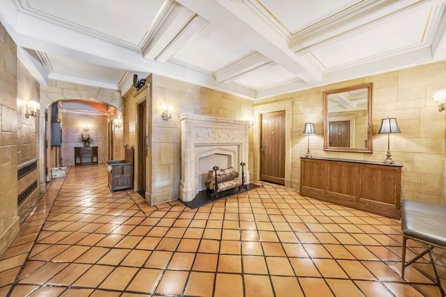 interior space featuring tile walls, coffered ceiling, a high end fireplace, ornamental molding, and beamed ceiling