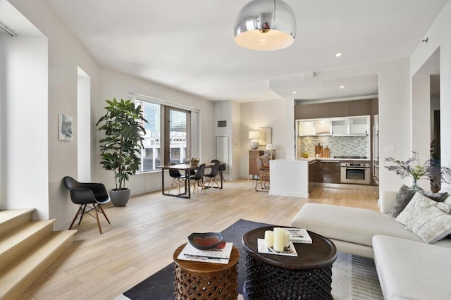 living room featuring recessed lighting, light wood-style flooring, and stairs