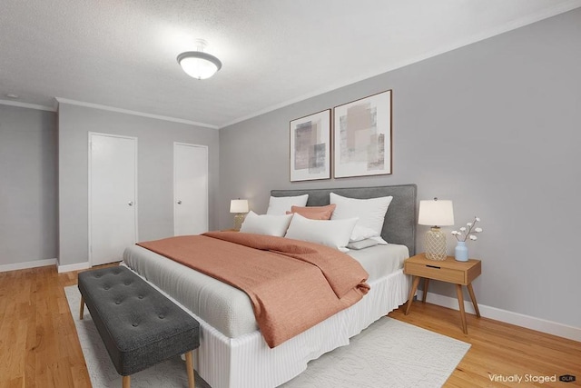 bedroom featuring a textured ceiling, ornamental molding, and light hardwood / wood-style floors