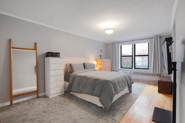 bedroom featuring ornamental molding, radiator heating unit, a textured ceiling, and hardwood / wood-style flooring