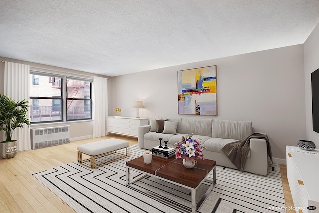 living area featuring baseboards, a textured ceiling, hardwood / wood-style floors, and radiator heating unit