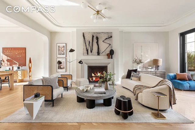 living room with crown molding and a warm lit fireplace