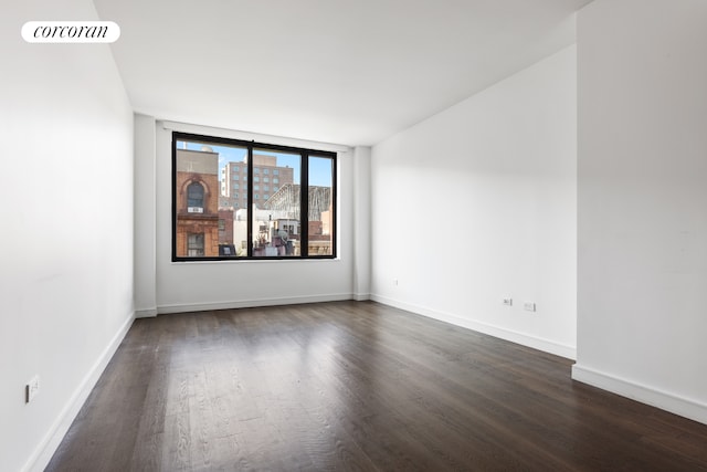 empty room featuring baseboards, visible vents, and dark wood-type flooring