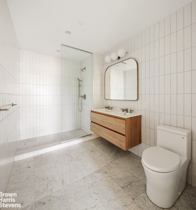 full bath featuring a tile shower, a sink, double vanity, toilet, and tile walls