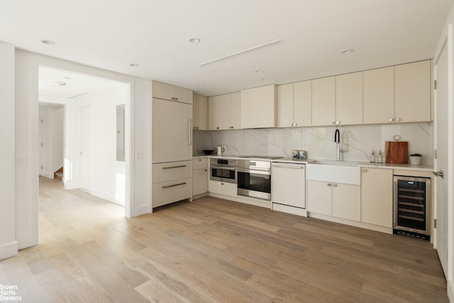 kitchen with white dishwasher, light wood-style flooring, wine cooler, and stainless steel oven