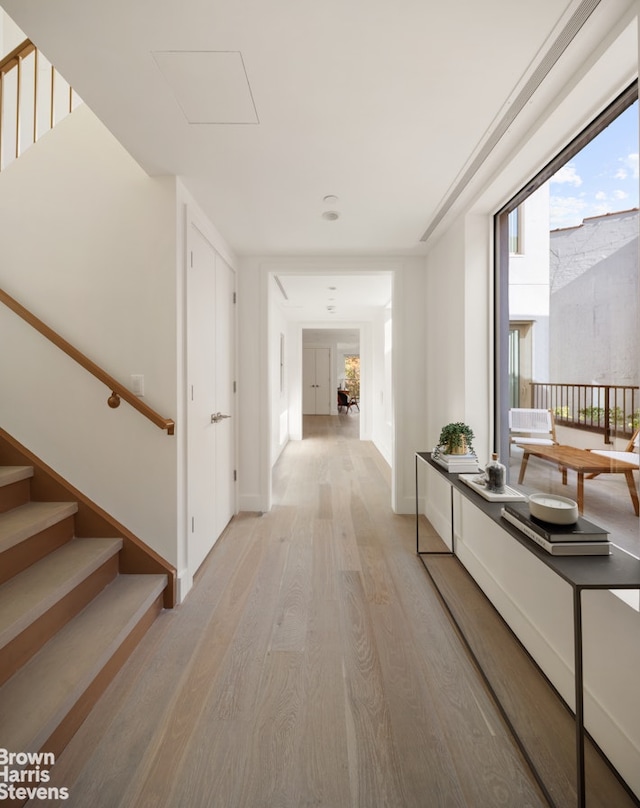 hallway with stairs, light wood-style flooring, and baseboards