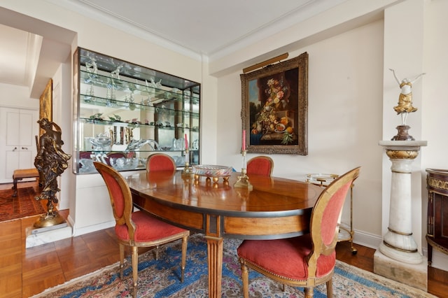 dining room featuring parquet floors, baseboards, and ornamental molding