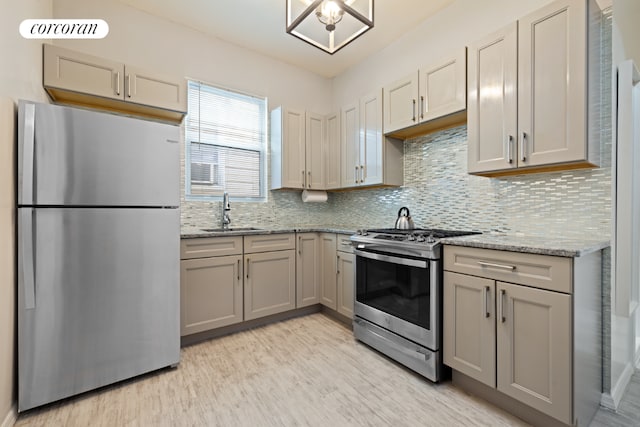 kitchen featuring sink, light hardwood / wood-style flooring, appliances with stainless steel finishes, light stone counters, and tasteful backsplash