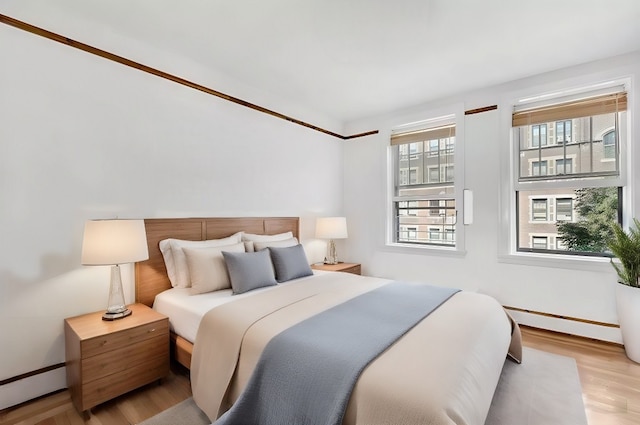 bedroom with light wood-style floors and a baseboard radiator