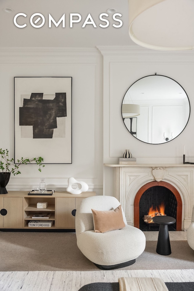 living area featuring carpet floors, ornamental molding, and a fireplace