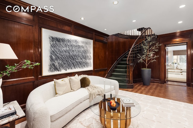 living area with recessed lighting, wooden walls, and stairs