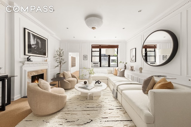 living area with carpet flooring, ornamental molding, a fireplace, and a decorative wall