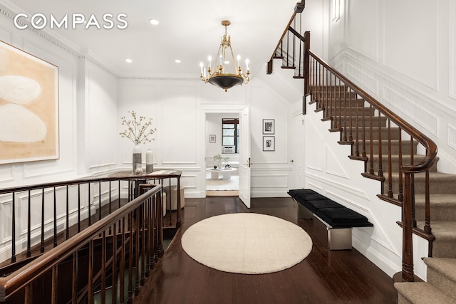 staircase featuring a decorative wall, a chandelier, crown molding, recessed lighting, and wood finished floors