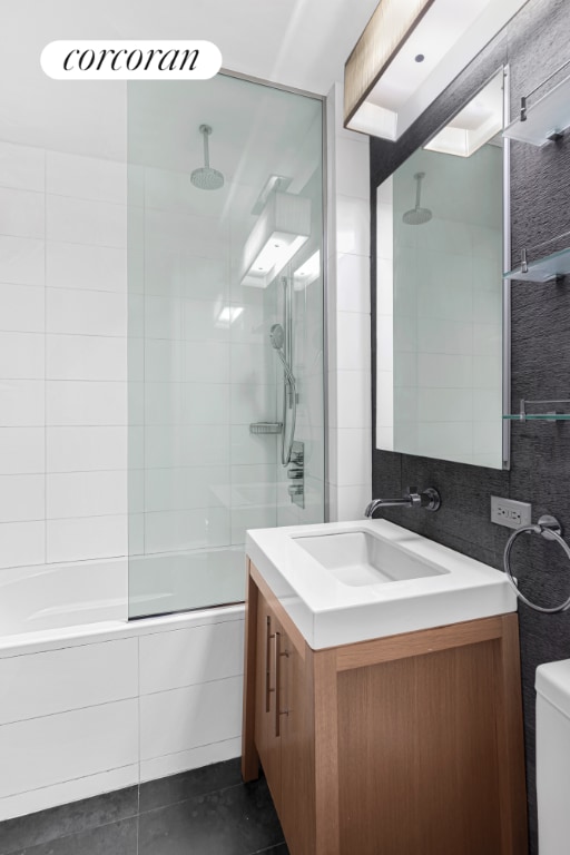 full bathroom with combined bath / shower with glass door, vanity, toilet, and tile patterned flooring