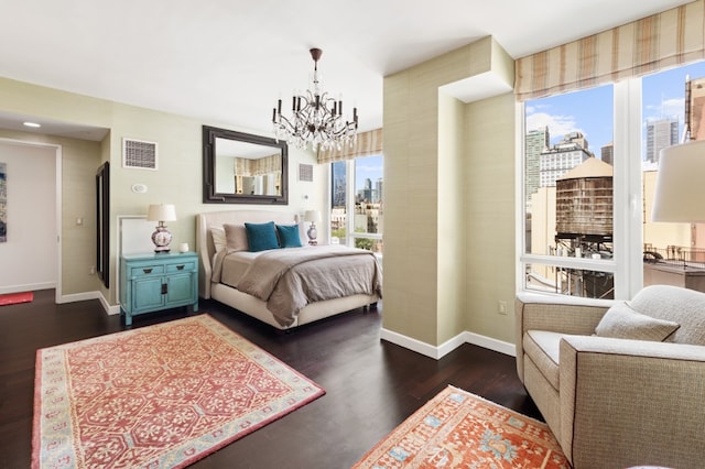 bedroom featuring visible vents, a view of city, dark wood-style floors, an inviting chandelier, and baseboards