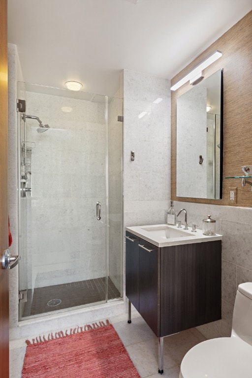 bathroom with toilet, a stall shower, tile walls, tile patterned flooring, and vanity