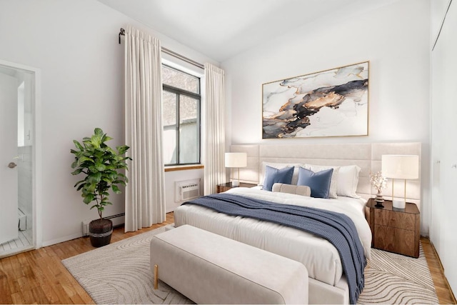 bedroom featuring a wall mounted air conditioner, a baseboard radiator, and light hardwood / wood-style flooring