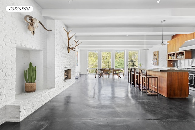 living area featuring finished concrete flooring, a fireplace, visible vents, and indoor wet bar