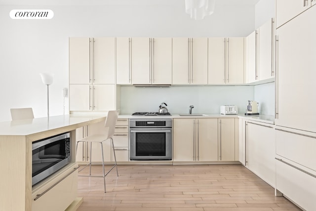 kitchen featuring appliances with stainless steel finishes, light hardwood / wood-style flooring, and sink