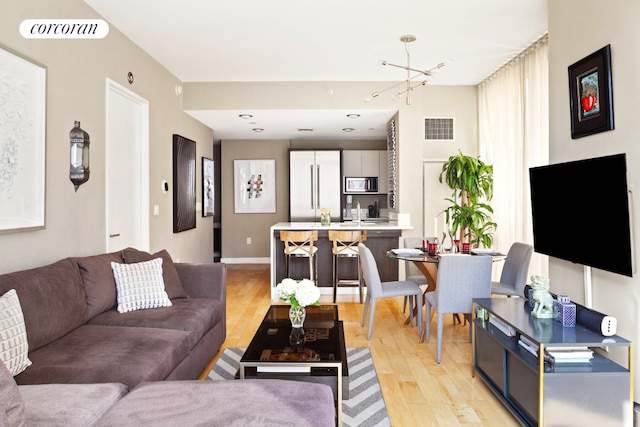 living room featuring a chandelier, sink, and light wood-type flooring