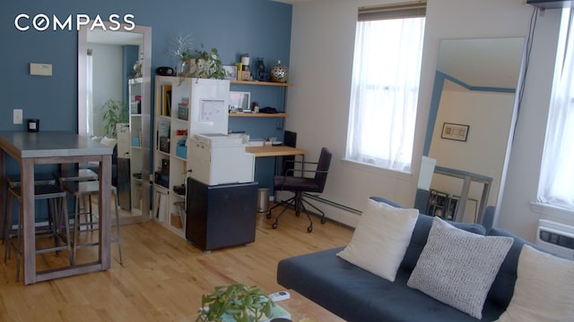 office featuring a baseboard heating unit, a healthy amount of sunlight, and light wood-type flooring