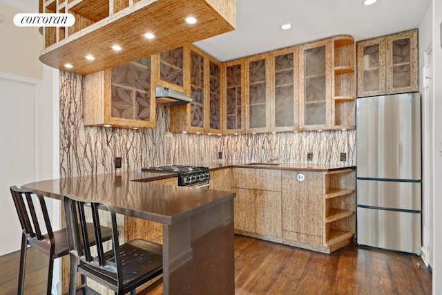 kitchen with dark wood-style floors, glass insert cabinets, a sink, stainless steel fridge, and range