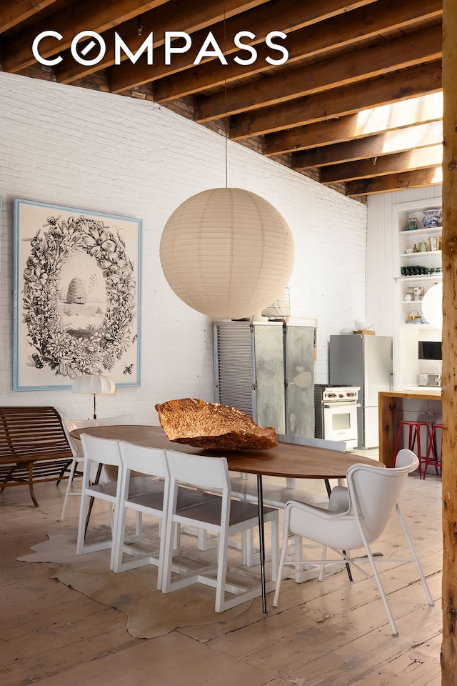 dining area featuring beamed ceiling and wood finished floors