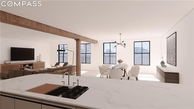 kitchen featuring sink, ornate columns, decorative light fixtures, a chandelier, and light stone countertops