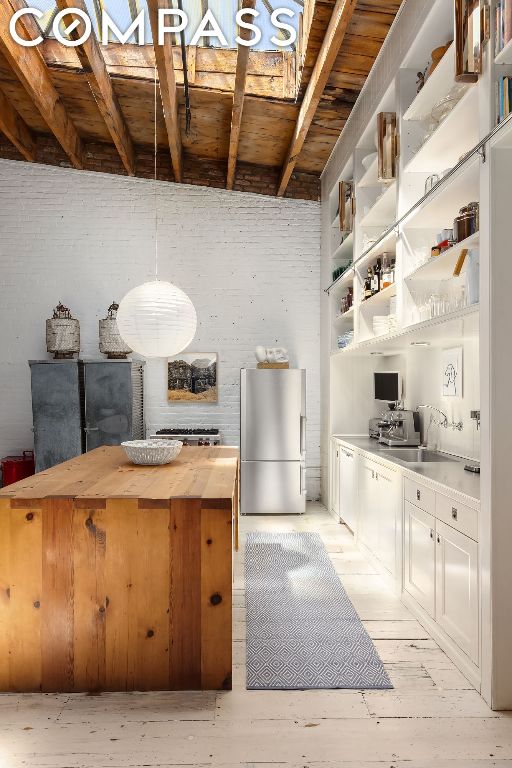 kitchen featuring butcher block countertops, stainless steel fridge, white cabinetry, decorative light fixtures, and wooden ceiling