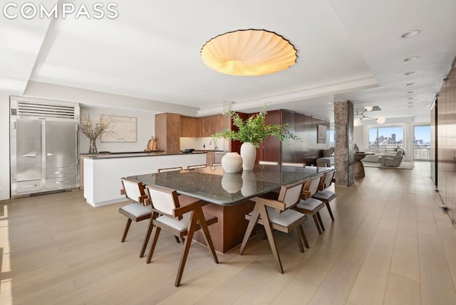 dining area with light hardwood / wood-style flooring and a tray ceiling