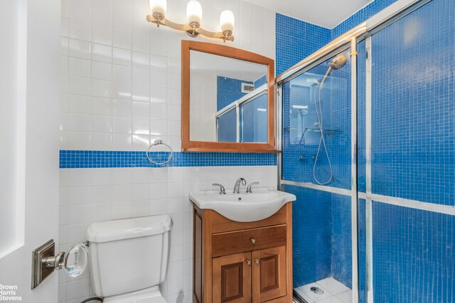 full bath with toilet, a shower stall, tile walls, and vanity