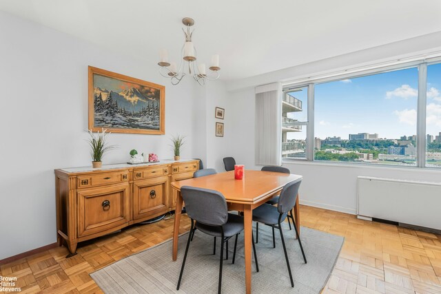 dining room with a chandelier, a view of city, and baseboards