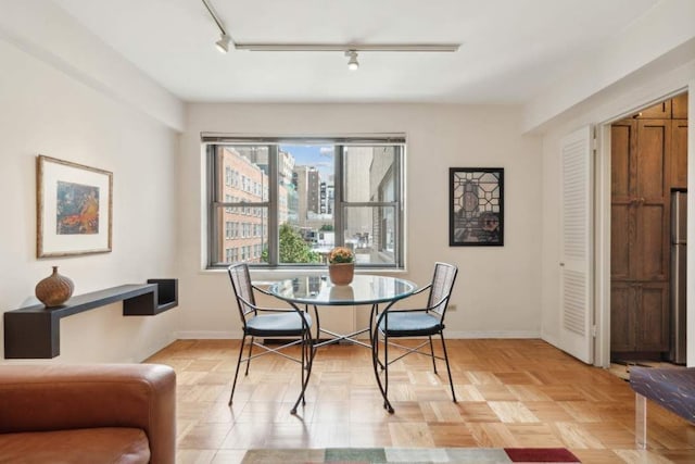 dining area with track lighting and light parquet floors