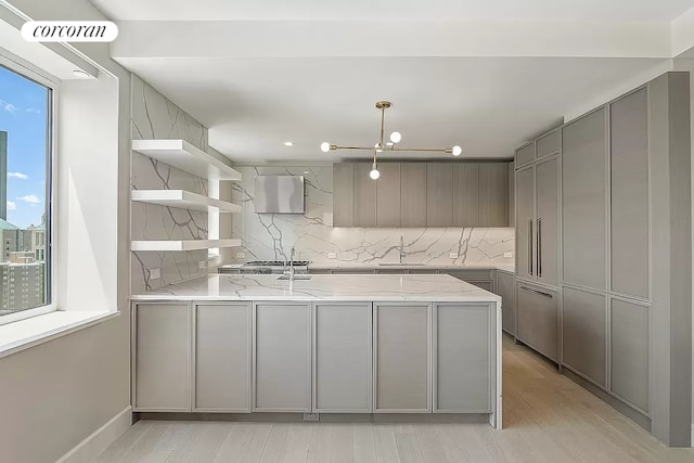 kitchen featuring tasteful backsplash, kitchen peninsula, light stone countertops, and gray cabinetry