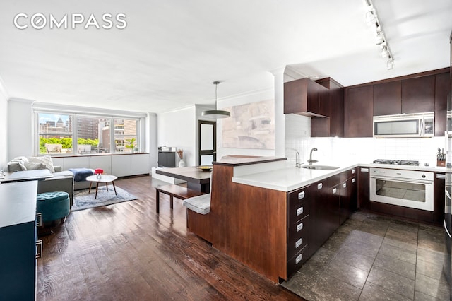 kitchen with a sink, tasteful backsplash, open floor plan, appliances with stainless steel finishes, and light countertops