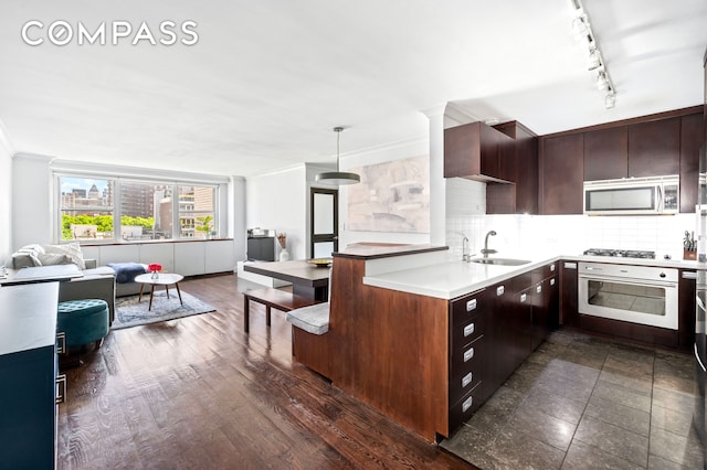 kitchen with stainless steel appliances, open floor plan, tasteful backsplash, a sink, and crown molding