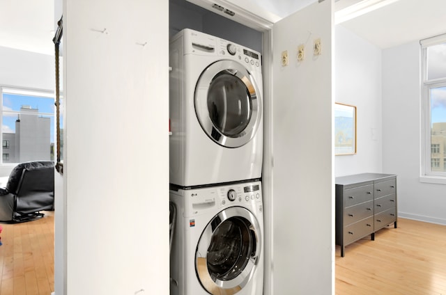 laundry area with stacked washer and dryer and light hardwood / wood-style floors