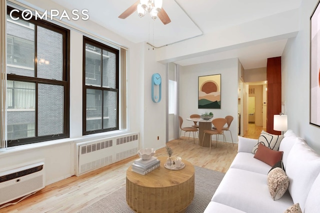 living room featuring a ceiling fan, light wood-type flooring, radiator heating unit, and a wall mounted AC