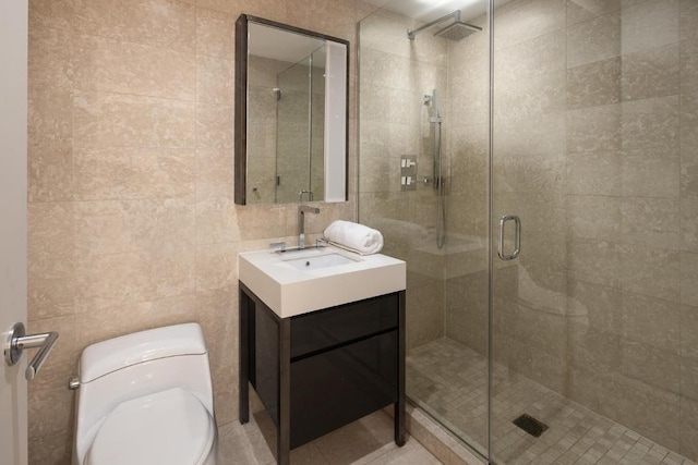 bathroom featuring a shower with door, vanity, tile walls, and toilet