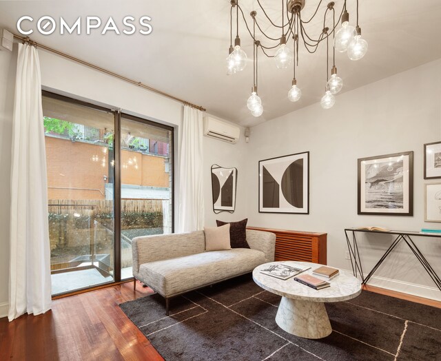 sitting room featuring hardwood / wood-style flooring and a wall unit AC