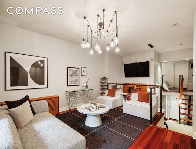 living room with wood finished floors, baseboards, a chandelier, and stairs