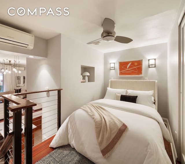 bedroom featuring ceiling fan, a wall unit AC, and wood finished floors