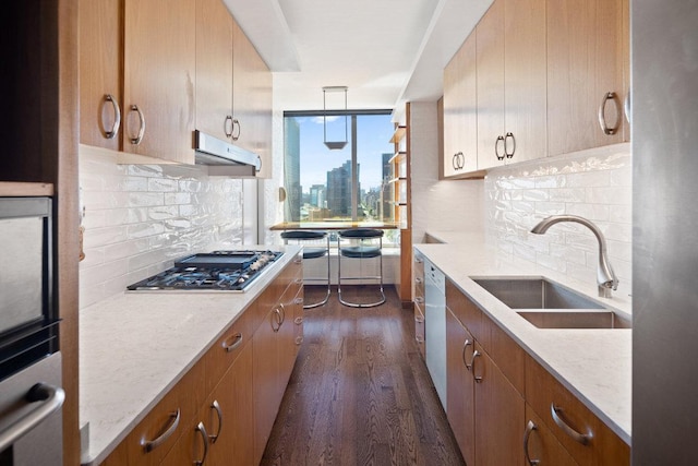 kitchen featuring pendant lighting, tasteful backsplash, sink, light stone counters, and dark wood-type flooring