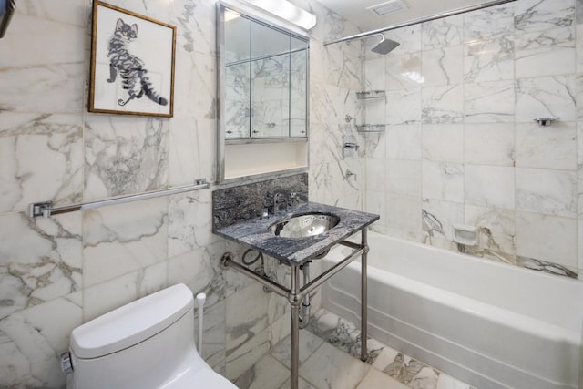 full bathroom featuring tiled shower / bath, sink, tile walls, and toilet