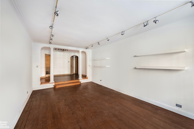 unfurnished living room featuring ornamental molding, dark hardwood / wood-style flooring, and rail lighting