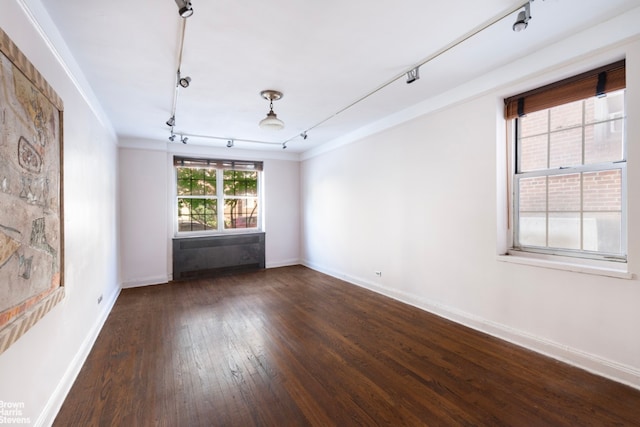 spare room with track lighting, ornamental molding, and dark hardwood / wood-style floors