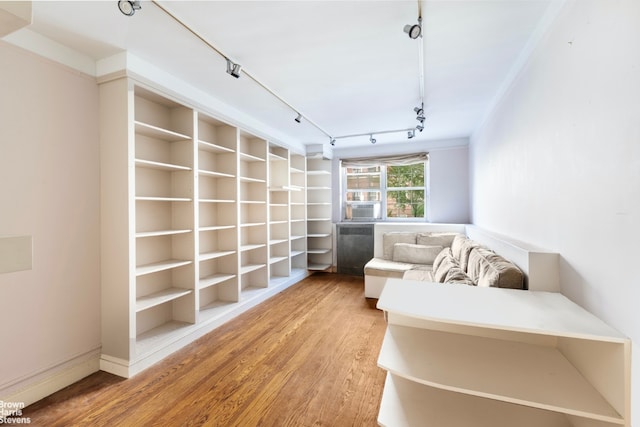 sitting room featuring hardwood / wood-style floors, track lighting, and built in features