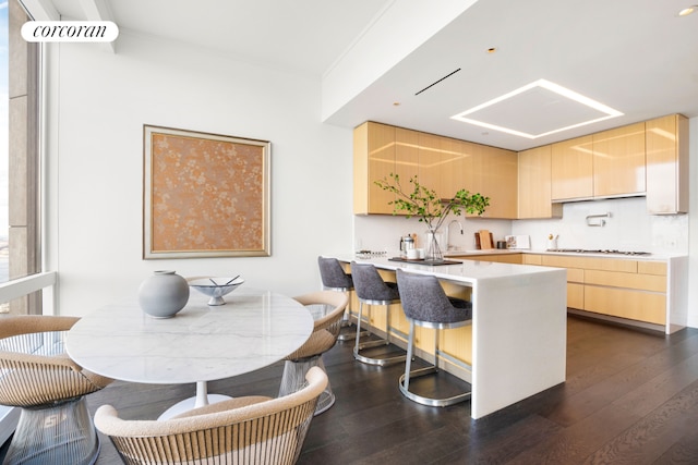 kitchen with dark wood finished floors, a peninsula, gas stovetop, light brown cabinetry, and light countertops